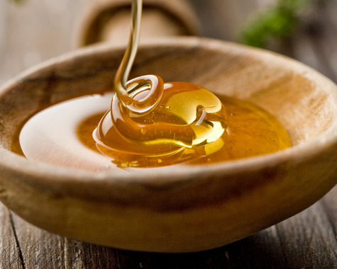 Honig das in eine Holzsch&uuml;ssel flie&szlig;t